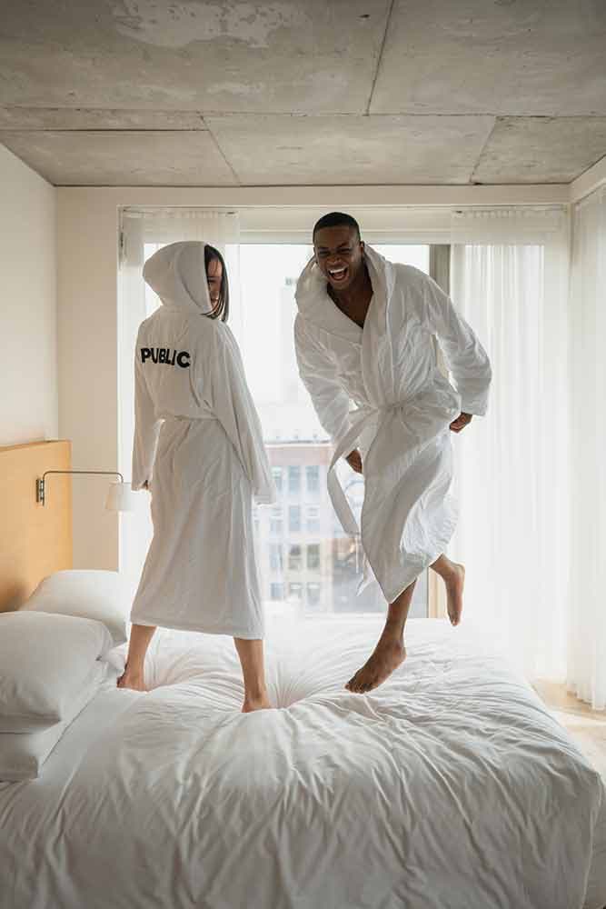 couple jumping on bed in Public hotel robes